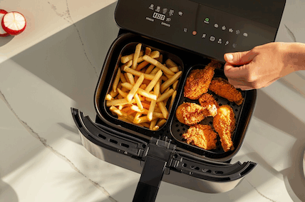 Ninja Dual Zone Airfryer Test. Ein Airfryer mit zwei Fächern. In dem linken Fach sind Pommes, in dem rechten Fach sind Chicken Wings.