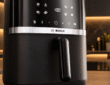 Bosch Serie 4 Airfryer Test - Die Bosch Heissluftfriteuse steht auf einer schwarzen Küchenplatte in einer modernen dunklen Küche.